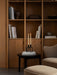 Kubus Line candlestick on a side table beside an Ingeborg Lounge Chair and Footstool, in front of a large wooden bookcase.