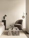 Lifestyle image of a Tearoom Lounge Chair, Plinth Low table in Grey Galaxy marble, and a TR Bulb Suspended Wall Lamp.