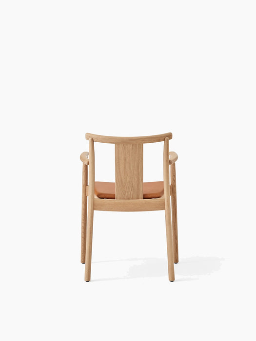 Rear view of the Merkur Dining Chair with Armrests in natural oak, featuring a tan leather seat pad on a white background.