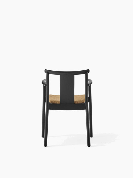 Back view of the Merkur Dining Chair with Armrests, featuring a black oak frame and a seat upholstered in Audo Bouclé 06.