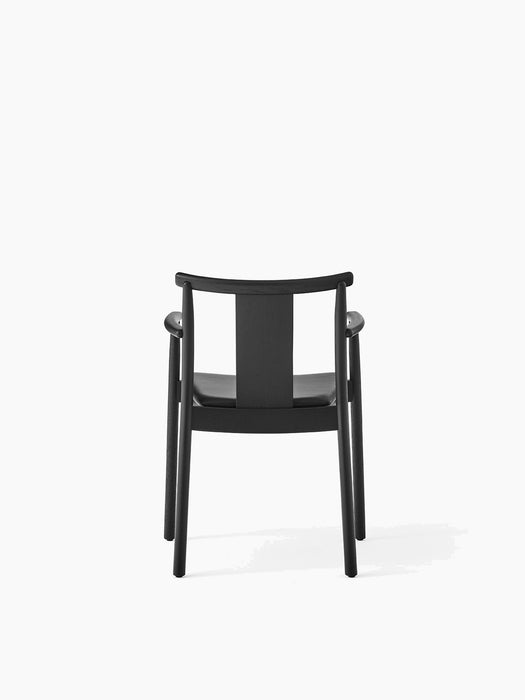 The Merkur Dining Chair with Armrests in black stained oak with a black leather seat, viewed from the back.