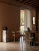 Two light oak Merkur Dining Chairs at a dark Androgyne Dining Table in a warmly lit room with a marble Plinth Pedestal.
