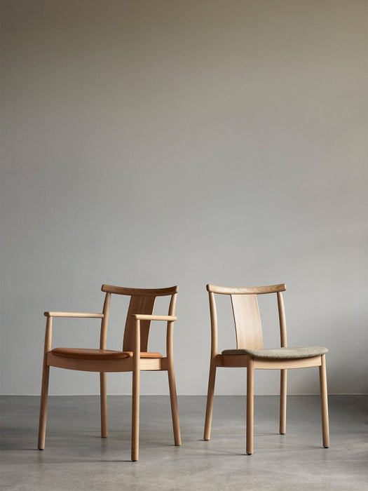 Two Merkur Dining Chairs in natural oak. One has armrests and a leather seat, the other has a fabric seat and no armrests.