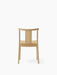 Back view of the Merkur Dining Chair in natural oak, showing its simple wooden frame, curved top rail, and central back slat.