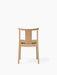 Back view of the Merkur Dining Chair in natural oak, featuring curved backrest and textured, beige bouclé upholstered seat.