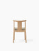 Back view of the Merkur Dining Chair in natural oak, featuring a curved backrest and a light grey upholstered seat.