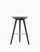 A front-facing image of the ML 42 Bar Stool, featuring a black stained beech finish, a sculptural seat, and a steel footrest.