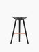 A front-on view of the ML 42 Bar Stool in black stained beech. The 3-legged stool has a moulded seat and a copper footrest.