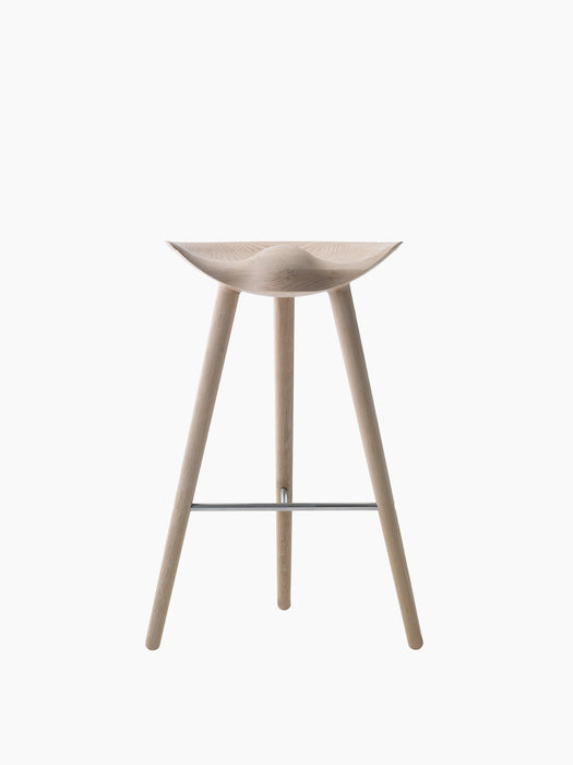 The ML 42 Bar Stool in soap-treated oak, viewed from the front, with a sculptural seat, three legs, and steel footrest.