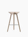 The ML 42 Bar Stool in soap-treated oak, viewed from the front, with a sculptural seat, three legs, and steel footrest.