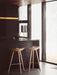 Two light oak ML 42 Counter Stools sit at a dark kitchen island. On the counter is a Kubus 8 candelabra and Kubus Bowl.