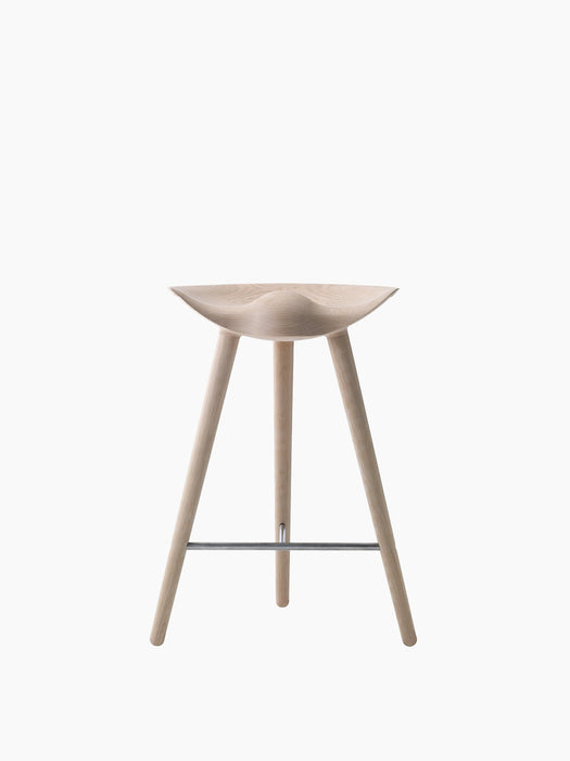 A front-on shot of the ML 42 Counter Stool in light oak, with a sculpted seat, three legs, and a steel footrest.