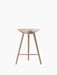 Front view of the ML 42 Counter Stool in light oak, featuring a sculptural seat, three legs, and a copper footrest.