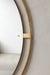 A close-up of the Nimbus Mirror, highlighting the polished brass halo frame and mounting detail against a textured grey wall.