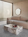 A modern living room with a beige Offset Sofa, a marble Plinth coffee table, and a round Nimbus Mirror on a concrete wall.
