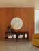 A lifestyle setting showing a Nimbus Mirror on a wood-panelled wall, above a black Zet Shelf with a JWDA Lamp and Aer Vase.