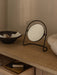A Nimbus Table Mirror sits on a wooden console table next to a Triptych Bowl, with an open drawer revealing a Divot Tray.