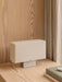 Nonna Table Lamp with a rectangular sand-coloured shade on a light wood desk against a matching wood-panelled wall.