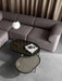 A modern living room with two glass NoNo Tables nested by a grey sofa, with a hanging lamp and taupe curtain.