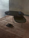 Two oval NoNo Tables, one large and one small, with dark glass tops, styled in a room on a brown rug with a Moon Vase.