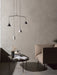 The black NoNo Table styled with books and a vase, next to a beige armchair. A contemporary pendant light hangs above.