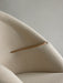 A close-up of the Oda Lounge Chair, showing the smooth wooden armrest seamlessly integrated into the light beige upholstery.