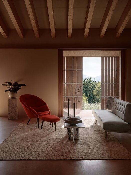 Red Oda Lounge Chair and Radiohus Sofa in a rustic room with an Androgyne Table, Plinth Pedestal, and open doorway.