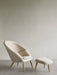 The Oda Lounge Chair and matching Oda Ottoman, upholstered in a cream fabric with natural oak legs, in a minimalist room.