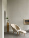 The Oda Lounge Chair and Oda Ottoman in cream fabric, styled in a minimalist room with grey walls and an arched doorway.