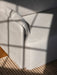 A close-up shot of a light-coloured fabric sofa. Sunlight casts a shadow from a window frame across the armrest and cushion.