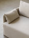 A close-up, high-angle shot of a sofa upholstered in a light beige, textured fabric, with soft cushions, on a concrete floor.