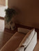 Overhead view of an Offset Sofa with Loose Cover, next to a Gravel Rug, and a Plinth Pedestal with a plant and books.