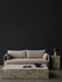 Beige Offset Sofa before a dark wall, styled with a Plinth Grand table, Plinth Tall table, and a Reverse Table Lamp.