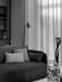 A black and white shot of the Offset Sofa in a living room setting, beside a marble Plinth and in front of a floor lamp.