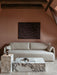 A light grey Offset Sofa against a terracotta wall below an abstract painting, with marble Plinth tables and a Column Lamp.