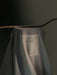 An artistic photograph of the Olfacte Scented Candle, Midnight Soak, shrouded in a light grey fabric with its label visible.