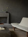 A light grey Pagode Sofa with wooden legs in a dark room, beside a Plinth Grand coffee table and a concrete fireplace.