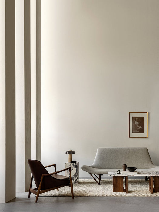 A minimal living room with the grey Pagode Sofa, Elizabeth Lounge Chair, Androgyne Table, and Plinth with Reverse Lamp.