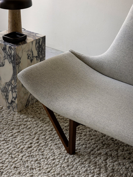 A close-up of the light grey Pagode Sofa on a textured rug, next to a marble Plinth Tall table with a Reverse Table Lamp.