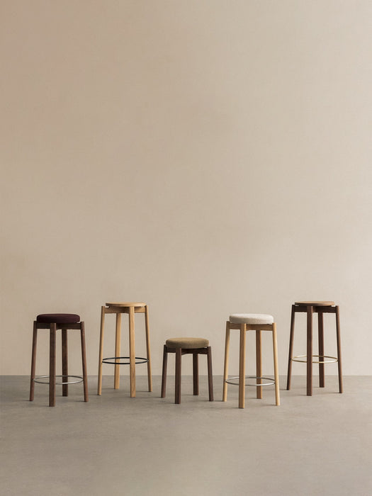 Five Passage Bar and Counter Stools lined up against a neutral wall, showing various heights, wood finishes, and upholstery.