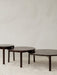 Three dark wood Passage Lounge Tables of different sizes arranged in a nesting formation on a light grey Houkime rug.
