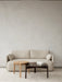 In a minimalist room, a beige Offset Sofa is styled with two Passage Lounge Tables, in oak and dark wood, on a textured rug.