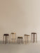 Five Passage Stools in a row against a beige wall, showcasing various heights, oak and walnut finishes, and upholstery.