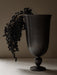 The Pavot Vase, a chalice-shaped vase in a dark metallic finish, styled with a bunch of dried berries draped over the edge.