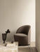 The Tearoom Lounge Chair Swivel in textured brown fabric beside a Plinth Low marble table with a Pavot Vase with foliage.