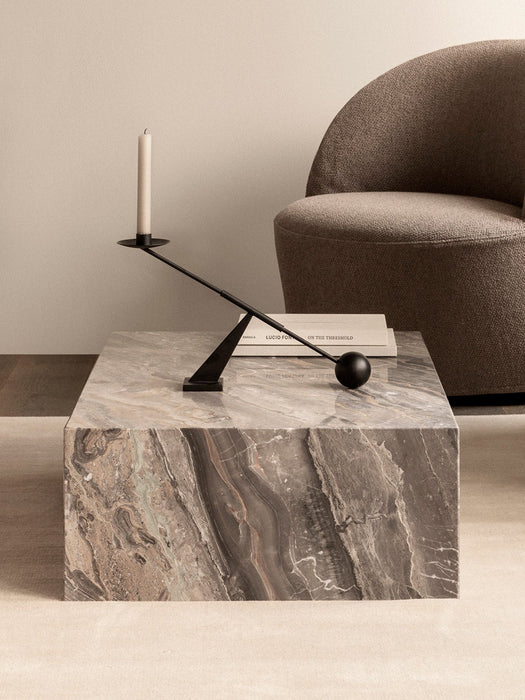 A Plinth Low coffee table in Grey Galaxy Marble, styled with a book and black candelabra, beside a brown Tearoom Lounge Chair