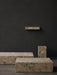 The Plinth collection in Kunis Breccia stone. Two Plinth Low tables, a tall plinth, and a shelf against a dark grey wall.