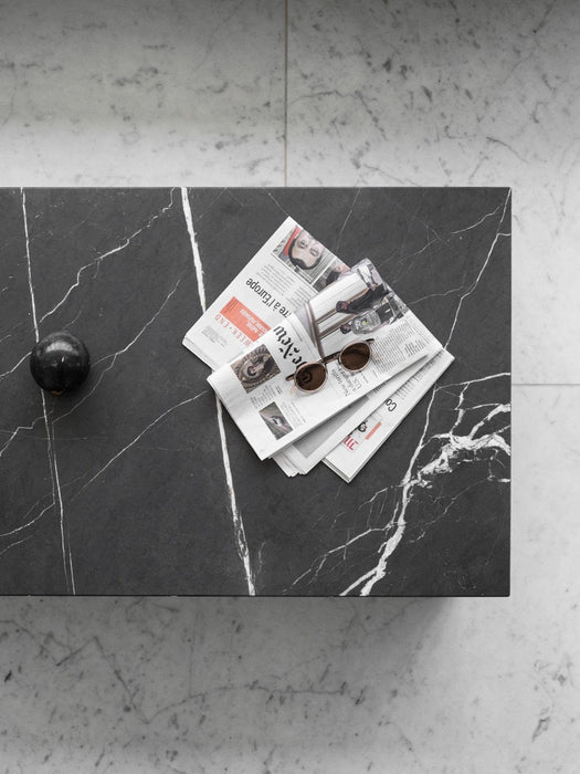 The Plinth Low in black marble, viewed from above, with a newspaper, sunglasses, and a decorative orb placed on its surface.