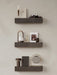 Three dark marble Plinth Shelves on a plain wall, styled with an Umanoff Candle Holder, lamps, a camera, and other decor.