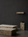 Minimalist composition of marble furniture: Plinth Low, Plinth Grand, Plinth Tall with a Triptych Bowl, and a Plinth Shelf.